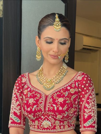 A front view of the bride with her sleek floral bun. The hair is pulled back cleanly to highlight her features and jewelry, making it a polished and sophisticated choice for any bride.
