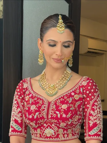 A front view of the bride with her sleek floral bun. The hair is pulled back cleanly to highlight her features and jewelry, making it a polished and sophisticated choice for any bride.