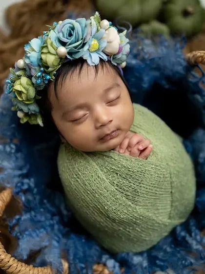 The baby is curled up peacefully in the basket, creating a cozy and secure feeling in this green and blue setup.
