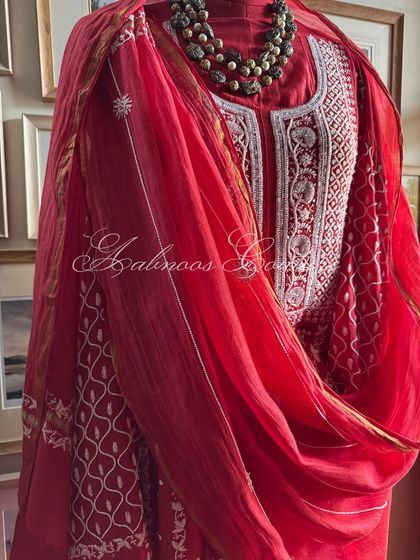A side view of the draped Anarkali, showing the interplay of the fabric and the rich red and white embroidery.