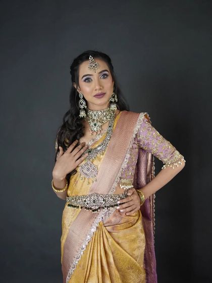 A model in a golden-yellow saree with a lavender blouse, wearing a stunning oxidized silver jewellery set.