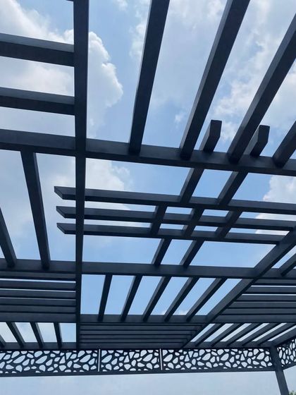 A view looking up through the pergola roof, showing the interesting shadow patterns it creates against the blue sky.