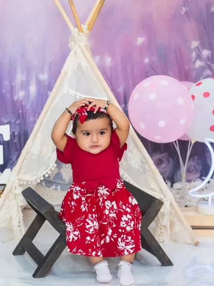 A cute moment as the baby girl adjusts her headband during her pre-birthday session.