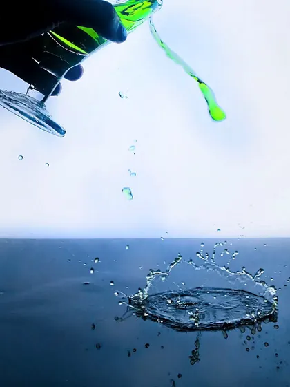 A creative take on a splash shot, capturing a green liquid being poured out of a tilted glass, creating an artistic and abstract sense of motion.