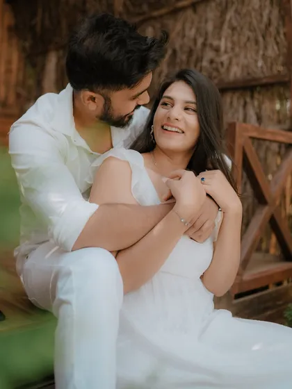 A moment of pure, uninhibited laughter on a rustic wooden porch. Dressed in coordinated white, this couple's joy is infectious, showcasing a perfectly candid moment from their pre-wedding shoot.
