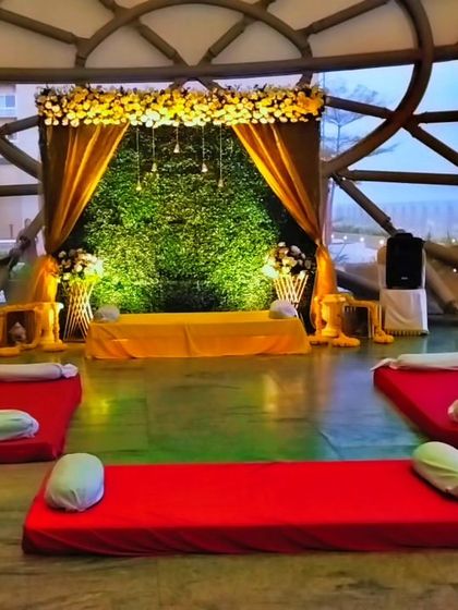 We created this unique Haldi or Sangeet setup inside a geodesic dome. The stage features a greenery wall with yellow drapes, complemented by low seating with bolsters for a comfortable and festive gathering.