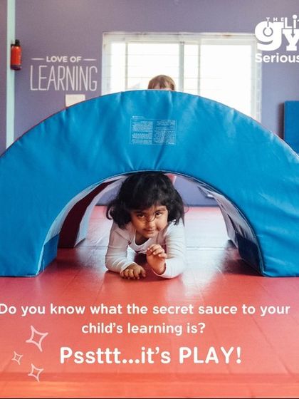 A young girl peeks out from under a soft play tunnel, her eyes full of curiosity. We use play-based learning to make every activity an adventure, teaching problem-solving and spatial awareness.