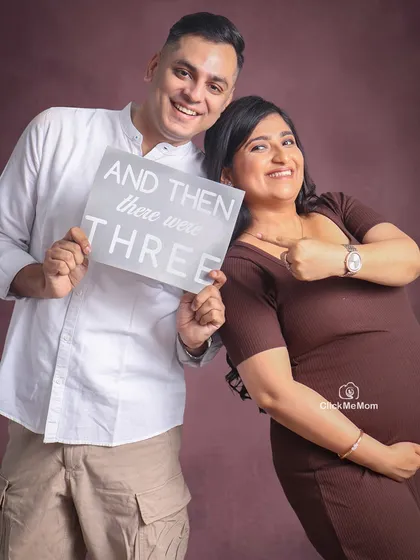 Let's celebrate your growing family with joy and playfulness. Using simple props like this "And then there were three" sign adds a personal and heartwarming touch to your maternity photoshoot, telling the story of your new chapter.