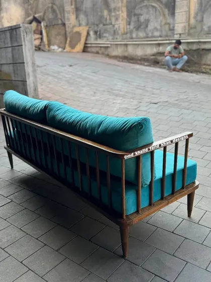 A mid-century style sofa with a spindle back, upholstered in a bright turquoise fabric.