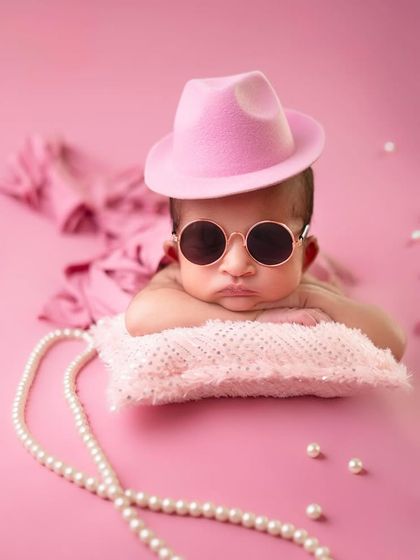 That's what a little boss baby looks like. With a stylish pink fedora and cool shades, this little girl is ready to take on the world.