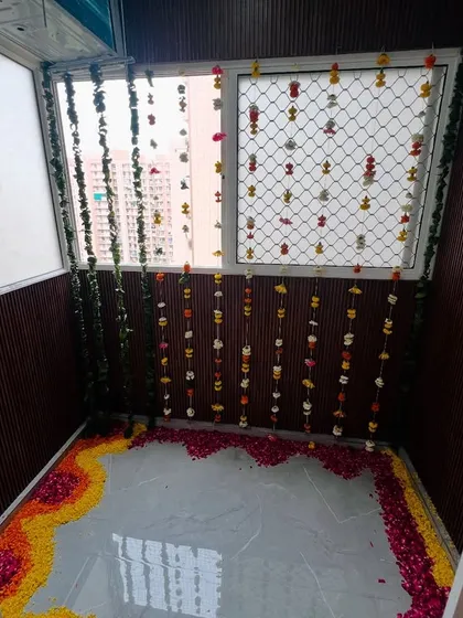 A balcony space decorated with flower strings and a petal rangoli on the floor. I can transform any small space into a beautiful spot for rituals.