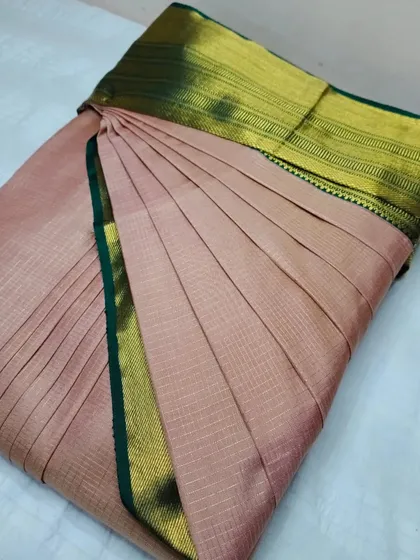 A simple and elegant pink silk saree with a green and gold border.
