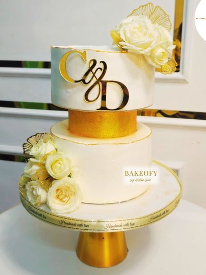 Elegance redefined. This two-tiered cake features a 1.5kg fresh fruit bottom tier and a 1.5kg vanilla top tier. The design is subtle and sophisticated, with white roses and delicate gold accents.