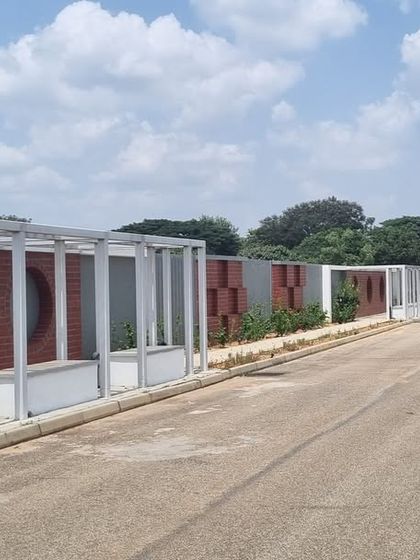 The finished boundary wall and walkway at Aamby City, featuring a unique design with brickwork and circular cutouts.