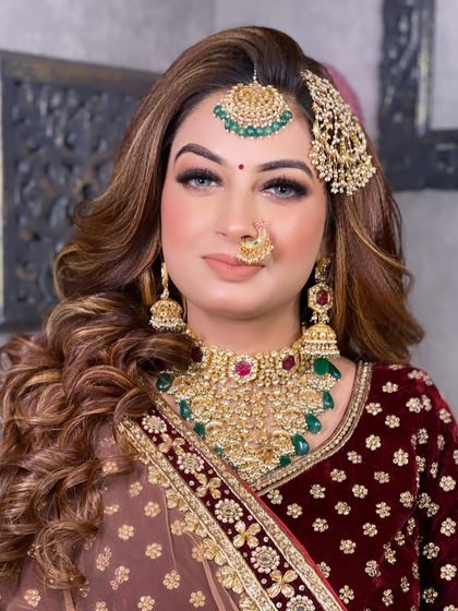 Another angle of the same bride, her hair styled in soft waves, complementing the heavy jewellery and rich outfit.