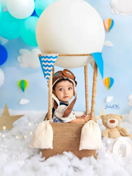 This little aviator is peeking out from his hot air balloon, ready for an adventure in the clouds. The pilot hat and dreamy blue backdrop create a magical scene for a one-year milestone session.