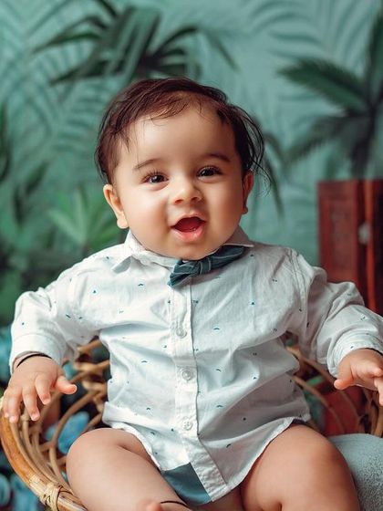 A happy and content baby boy in our tropical studio setup. The lighting is designed to highlight their adorable features.