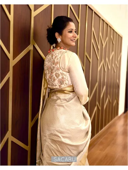 The back view of Pooja's ensemble, showing the intricate jari thread embroidery on the off-white velvet jacket.