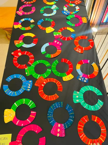 A stunning table display of African Masai-inspired neck collars, crafted with vibrant colors and patterns by our students.