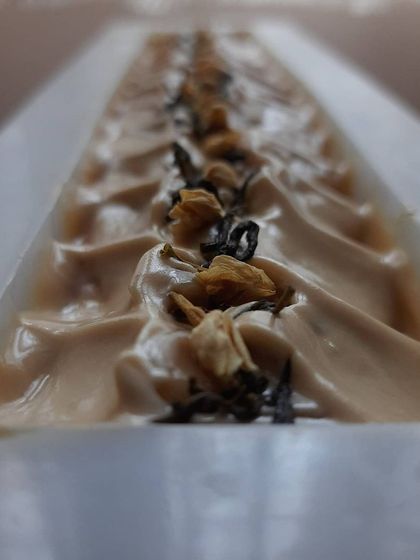 A close-up of my Earl Grey Tea soap loaf, freshly poured. I've topped it with real tea leaves and botanicals that complement its intoxicating, citrusy aroma.