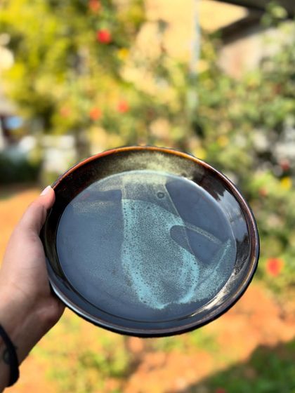 Our Tenmoku plate with a splash of Chun glaze. The deep, dark Tenmoku contrasts beautifully with the light, flowing Chun, creating a dramatic, artistic piece.
