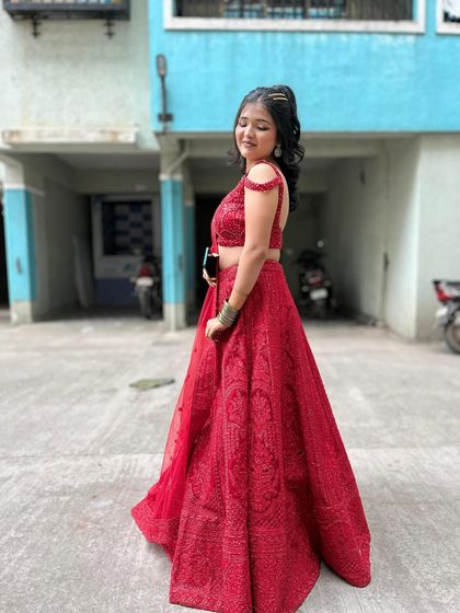 A happy client looking absolutely radiant in a classic red lehenga. This outfit is perfect for a wedding ceremony or a reception party.