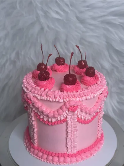 A still shot of the all-pink vintage cake. The different shades of pink in the piping add depth and texture, while the cherries on top provide a classic finishing touch.