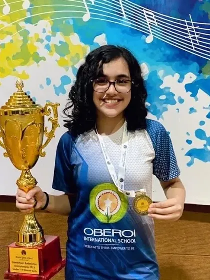 Our student Ariana Sood from the MCA center, holding her trophy and gold medal after winning the U-17 girls singles title.