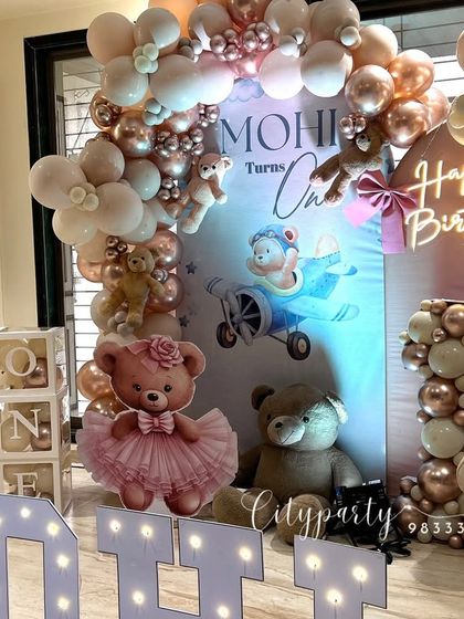 Another angle of the 'Mohi' teddy bear birthday setup, showcasing the 'ONE' letter blocks and the balloon-filled marquee number '1'.