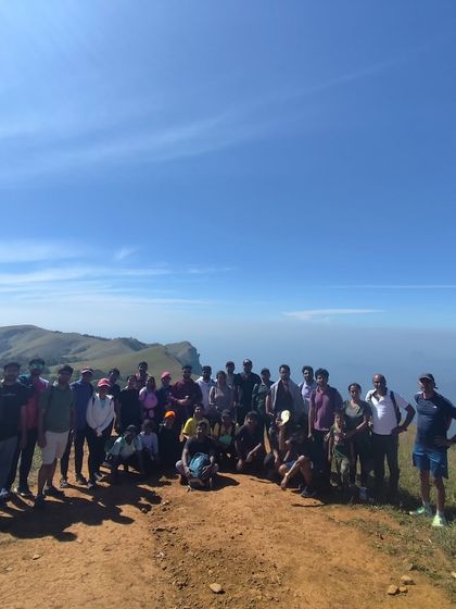 Another group photo on a clear day, showing the vastness of the sky and the mountains.