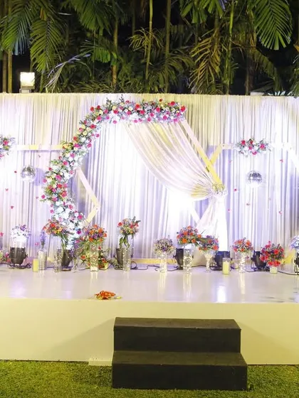 We designed this elegant reception stage for an intimate lawn wedding, creating a magical ambiance under the stars. The flowing white drapes, delicate floral arch, and soft lighting came together to produce a truly romantic setting for the couple's celebration.