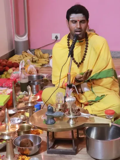 A priest chants sacred mantras into a microphone, filling the space with divine vibrations during a ceremony.