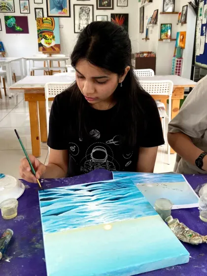 A student works on a beautiful ocean scene in our acrylics course, learning how to blend colors to create a realistic water effect.