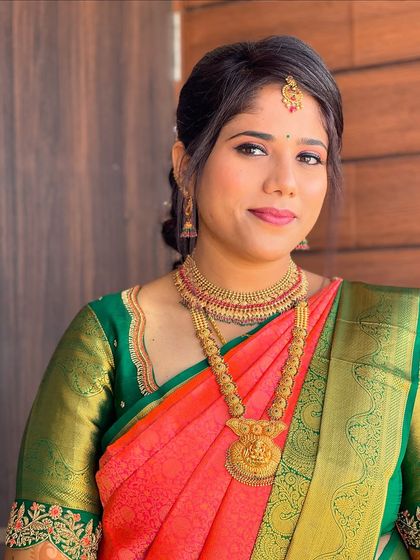 A simple and elegant welcome look for Gagana. The makeup is kept fresh and natural to complement her beautiful coral and green silk saree and traditional gold jewelry.