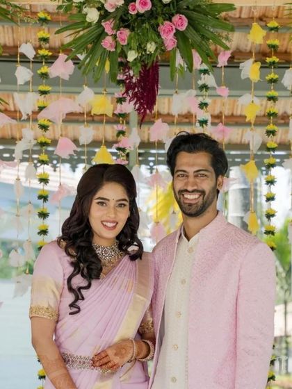 This shot captures the joy and radiance of the couple, framed by the vibrant floral archway and the soft, natural light of the venue.
