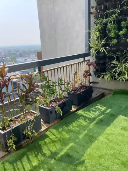 A closer look at the balcony garden, showing how the vertical wall of spider plants complements the darker foliage in the rectangular planters, all set against a maintenance-free artificial lawn.