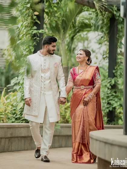 The couple walking together in a beautiful garden setting, hand in hand, looking picture-perfect in their traditional wedding attire.