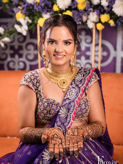 A happy bride showing her palms, adorned with intricate mehendi for her sangeet ceremony.