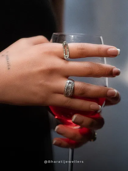 Embrace the brilliance of our Noya women's jewellery. This shot features our unique safety-pin inspired diamond ring alongside a classic channel-set diamond band, perfect for a chic evening out.