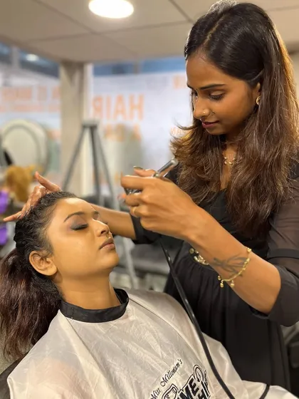 A student practices airbrush makeup techniques on a model, a skill we teach in our advanced makeup courses.