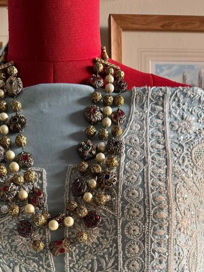 A close-up of the neckline, styled with a traditional multi-layered necklace.