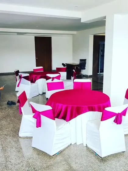 A close-up of the round table seating arrangement we provide for private parties. Each table is set with a clean tablecloth and surrounded by chairs with covers and sashes to match the event's color scheme.