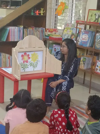 We use special tools like this traditional wooden puppet stage to make stories even more magical. Here, children are captivated as illustrations come to life, drawing them deeper into the narrative.