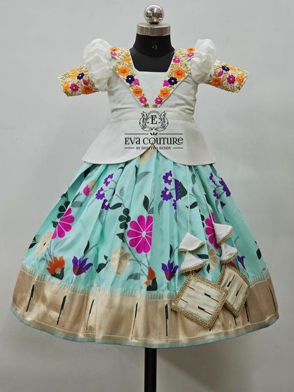 A white peplum blouse with colorful floral embroidery on the collar, paired with a pastel blue floral skirt.