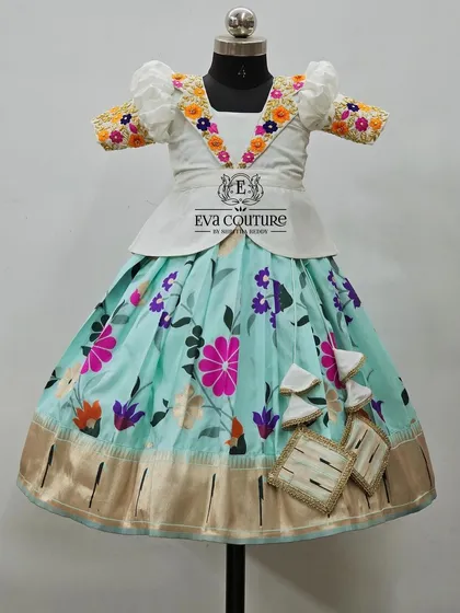A white peplum blouse with colorful floral embroidery on the collar, paired with a pastel blue floral skirt.