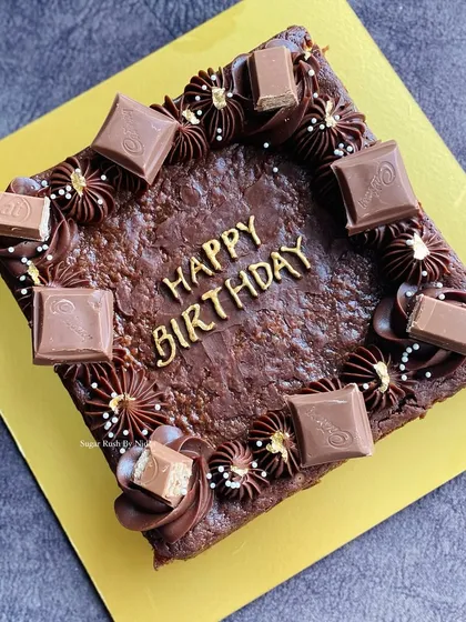 A 500g birthday brownie slab, decorated with golden "Happy Birthday" lettering and chocolate chunks. A great alternative to a traditional birthday cake.