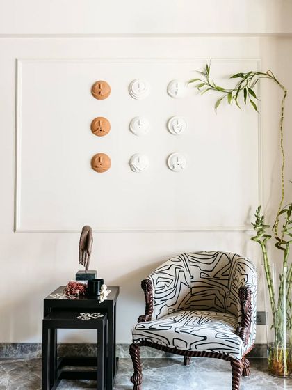 This quiet corner is a perfect example of how to use art and furniture to create a point of interest. The unique armchair with its graphic print is paired with a simple black side table and a three-dimensional wall art installation.