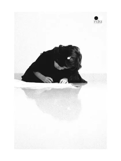 A quiet, artistic shot of one of the twins engrossed in coloring on the floor. The reflection on the glossy surface and the minimalist composition make this a powerful and unconventional child portrait.
