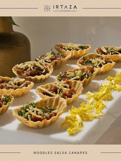 Noodles Salsa Canapés are a unique fusion appetizer. The crispy tart shell is filled with a tangy noodle and salsa mix, creating a surprising and delightful bite.