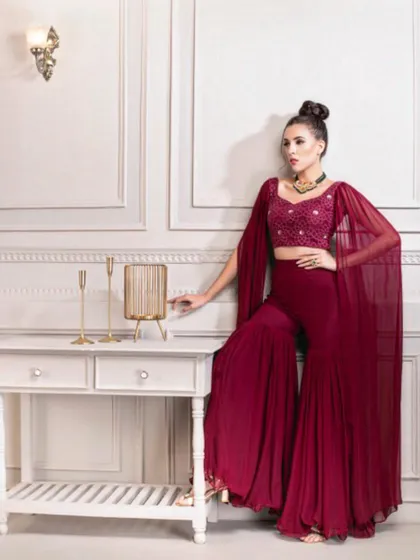 This look is for the modern bride who loves contemporary silhouettes. I styled this deep maroon sharara set, featuring dramatic cape sleeves and an embellished crop top, for a chic Sangeet or cocktail event.